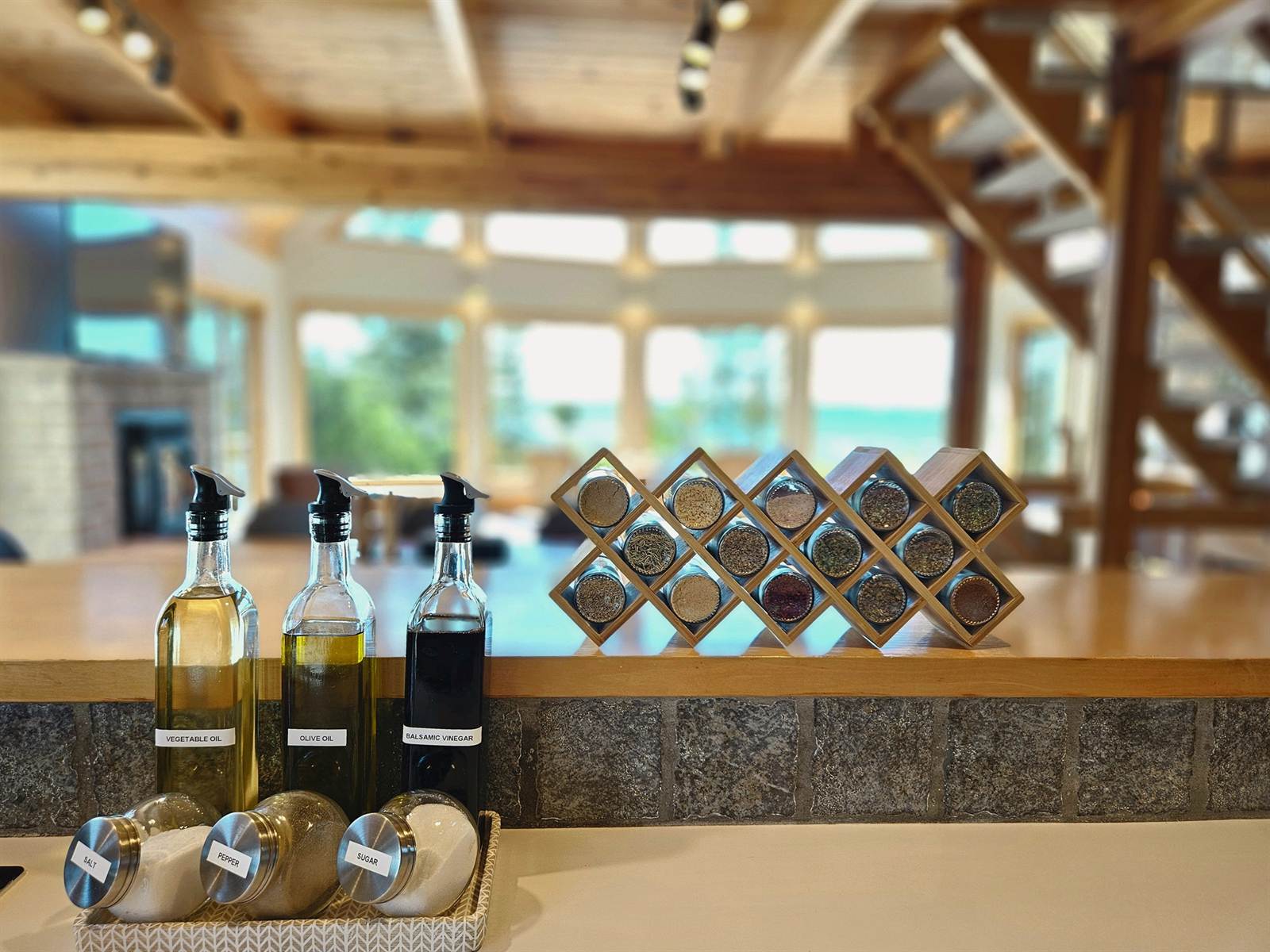 Kitchen counter with labelled oils and a wooden spice rack, great room beyond