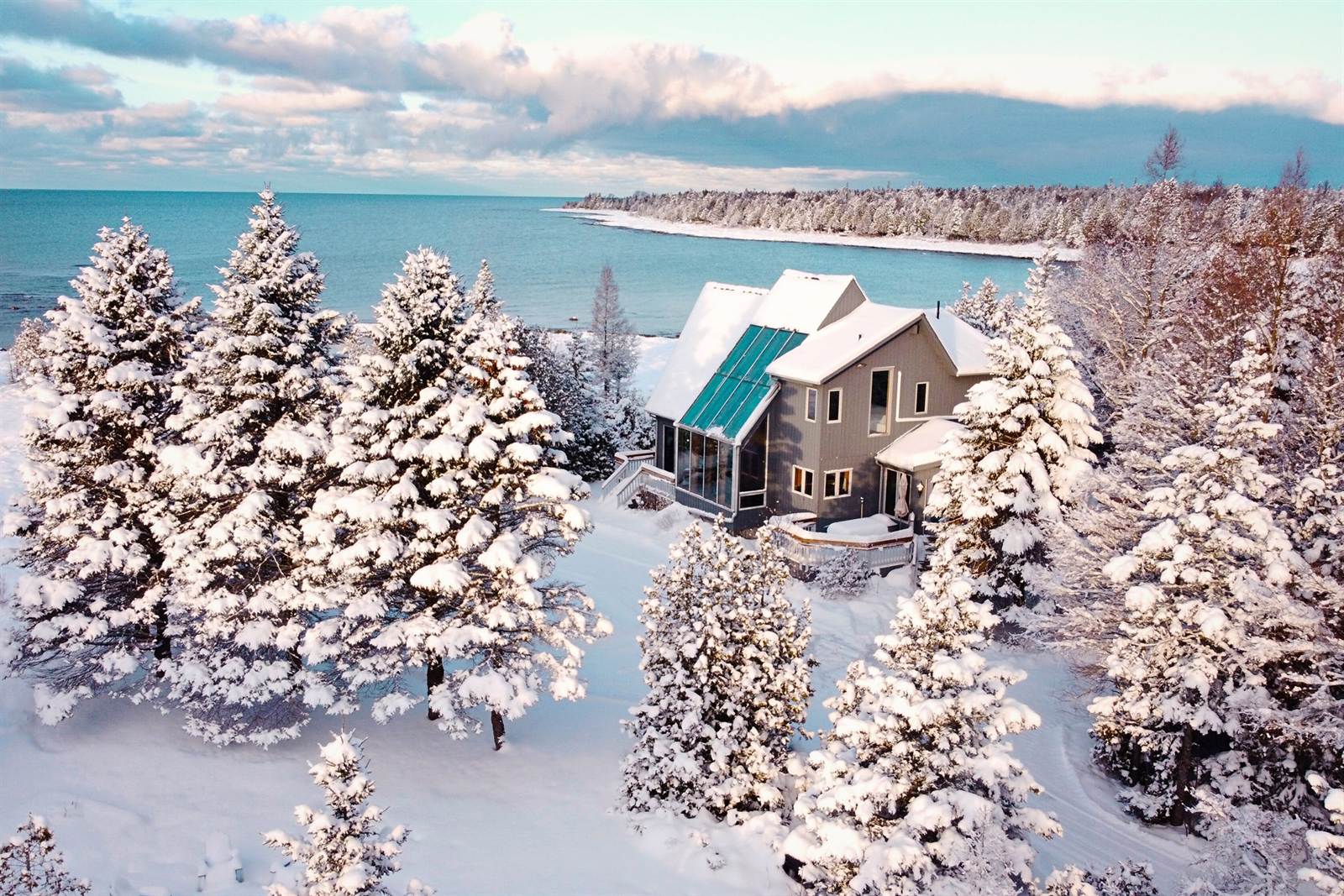 The cottage and snow-covered evergreens beside the winter bay