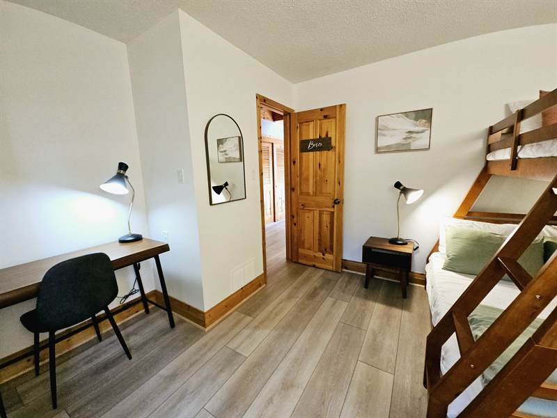 Bosco bedroom with desk, chair and lamp opposite a wooden bunk bed, arched mirror on the wall